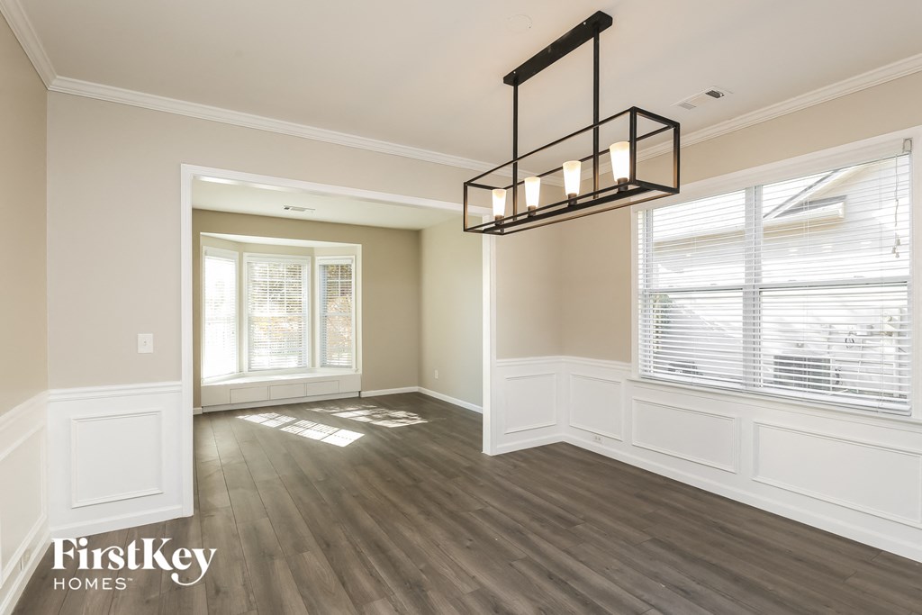 A well-lit room with wooden floors and a large window.