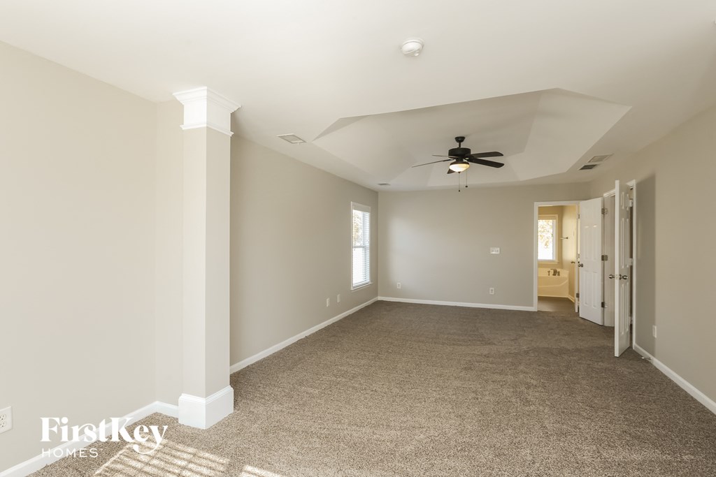 A spacious room with a ceiling fan and carpeted floor.