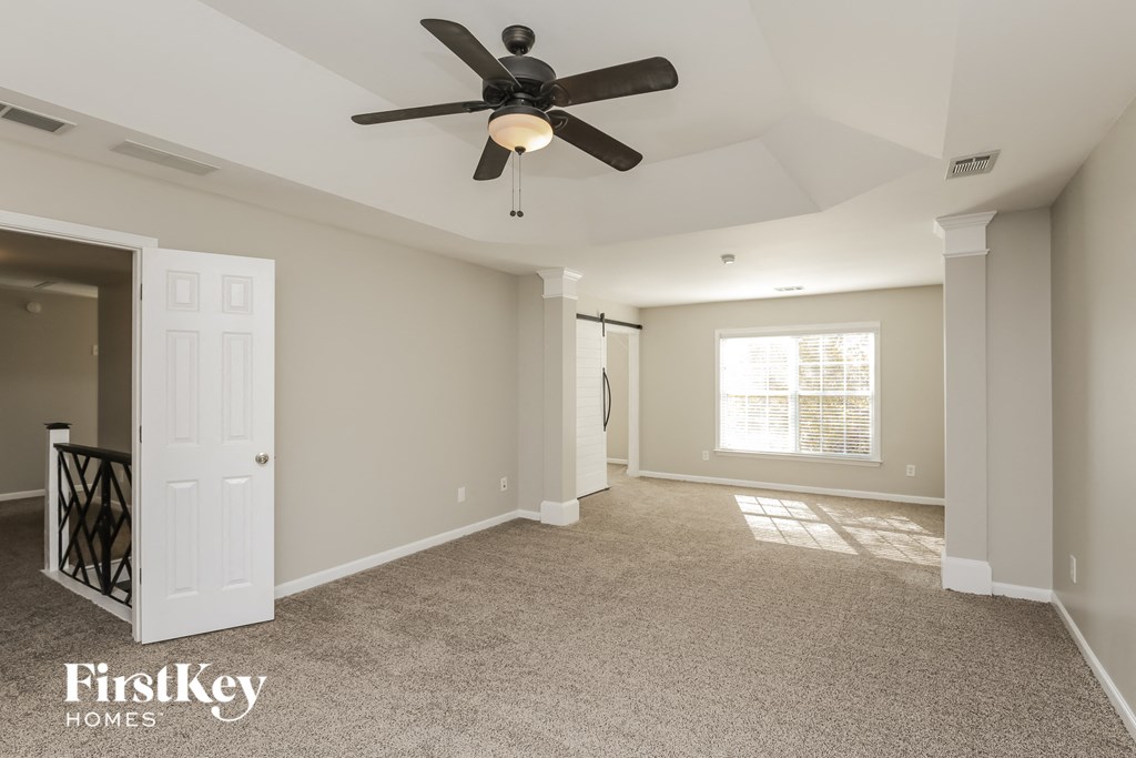 A spacious room with a ceiling fan and a door leading to another room.