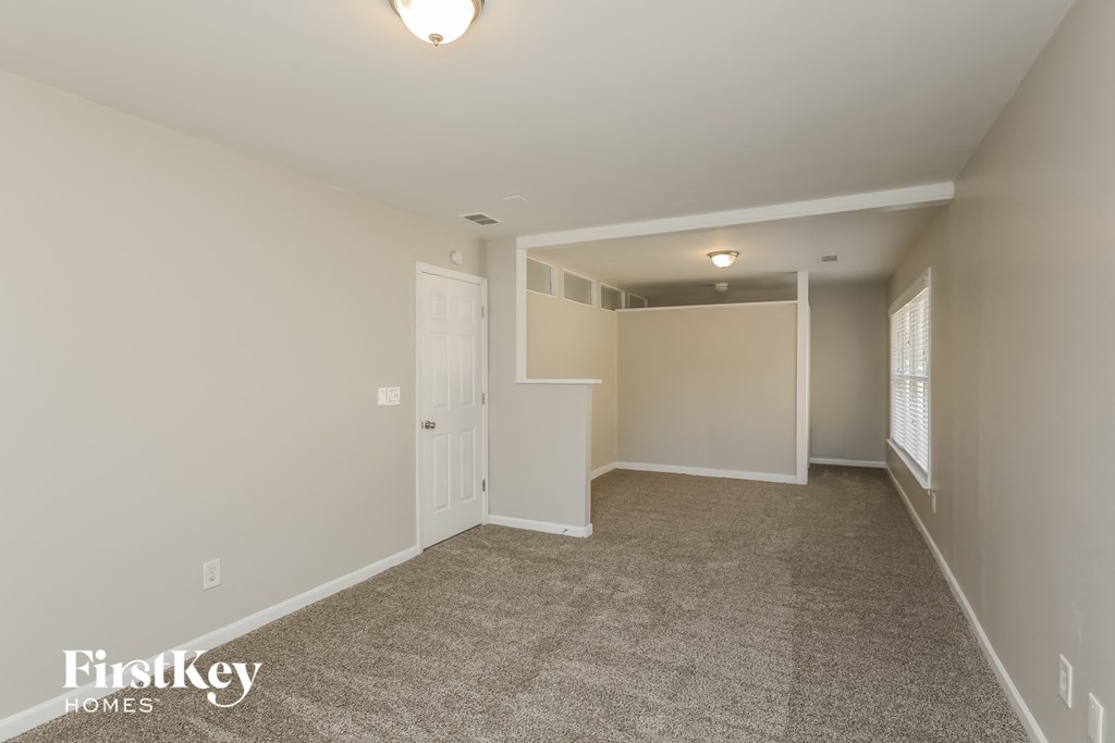 A room with a carpeted floor and a door leading to another room.