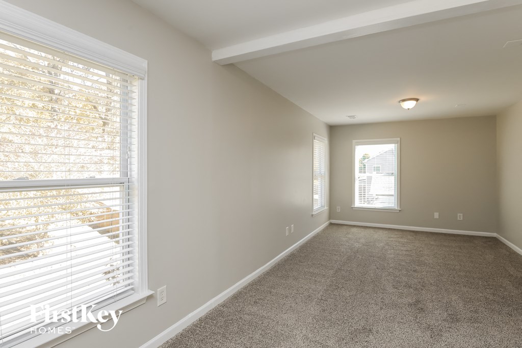 A room with a carpeted floor and a window with blinds.