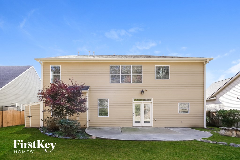 A beige house with a white door and a small tree in front.