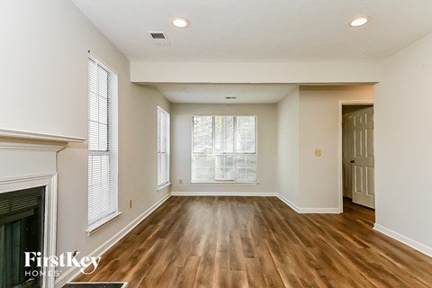 an empty living room with a fireplace and wood flooring