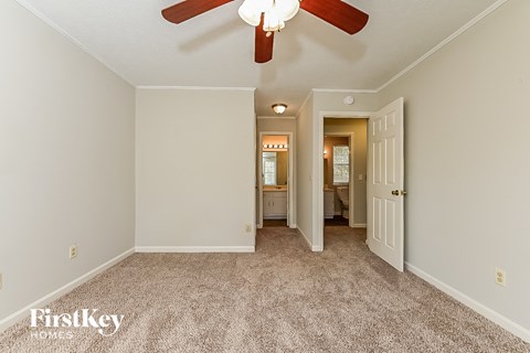 a master bedroom with carpet and a ceiling fan