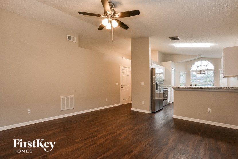 A spacious room with a ceiling fan and wooden flooring.