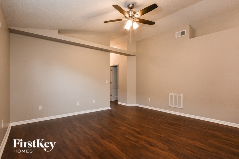 A spacious room with a ceiling fan and wooden flooring.