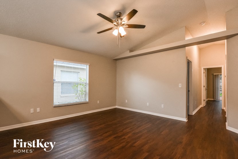 A spacious room with a ceiling fan and wooden flooring.