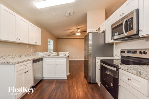 A kitchen with white cabinets and a granite countertop.