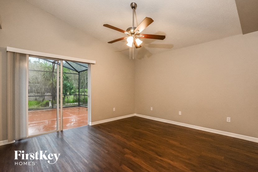 A room with a ceiling fan and sliding glass doors.