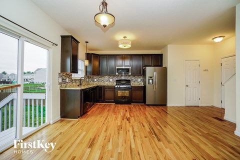 a kitchen with wooden floors and black appliances and a door to a balcony