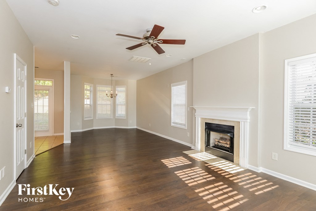 an empty living room with a fireplace and a ceiling fan