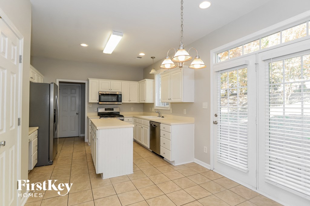 a large kitchen with white cabinets and a stainless steel refrigerator