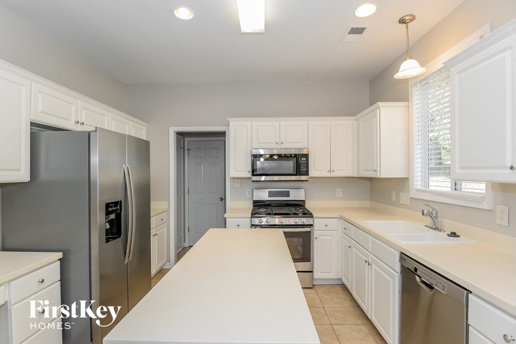 a white kitchen with stainless steel appliances and white counters
