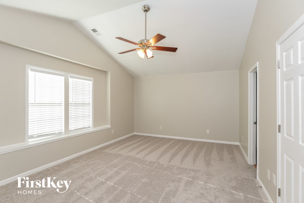 a empty living room with a ceiling fan and a window