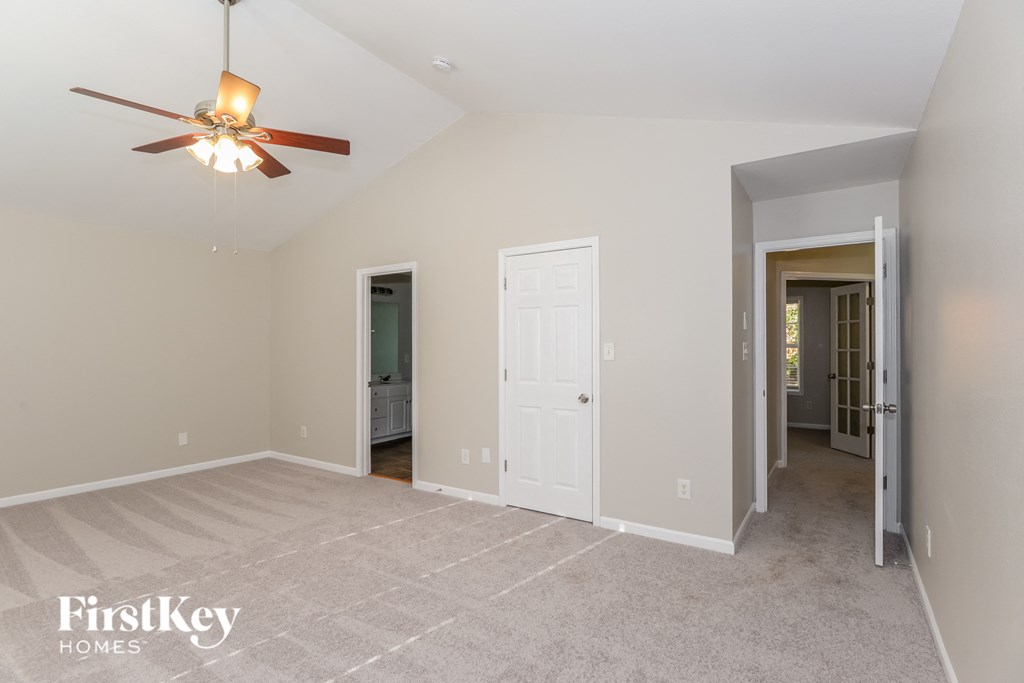a living room with a ceiling fan and a door into a hallway