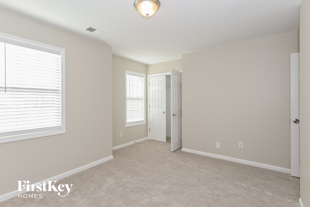 a bedroom with a carpeted floor and a white door and window
