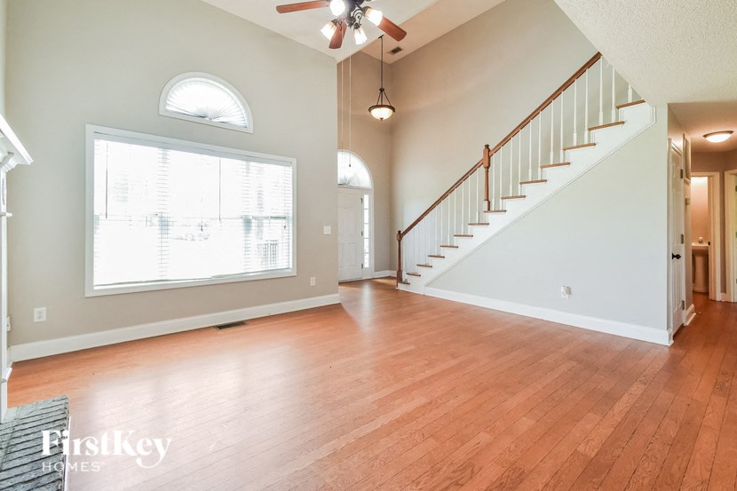 an empty living room with a large window and a staircase
