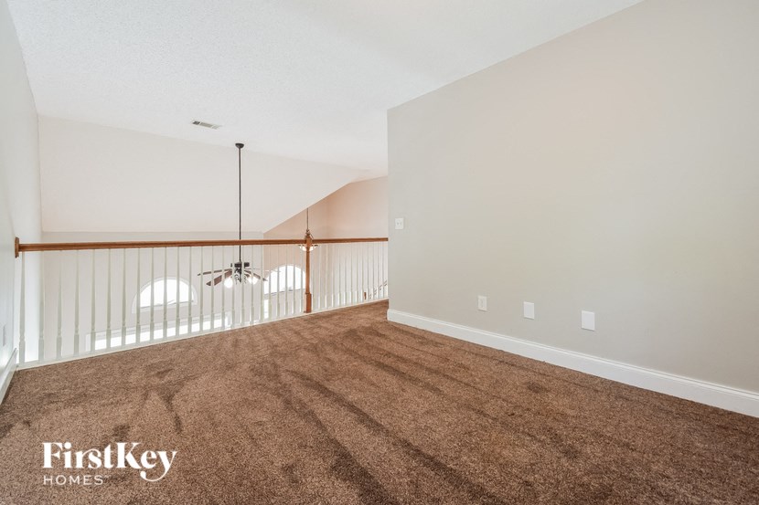 an empty living room with a carpeted floor and a ceiling fan