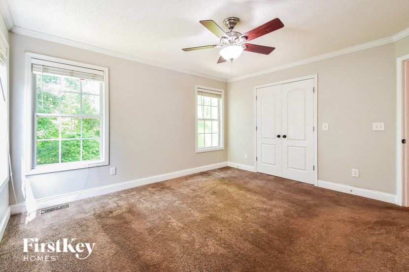 a carpeted living room with a ceiling fan and a window