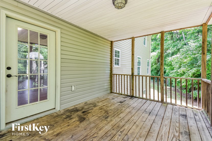 a covered porch with wood floors and a door