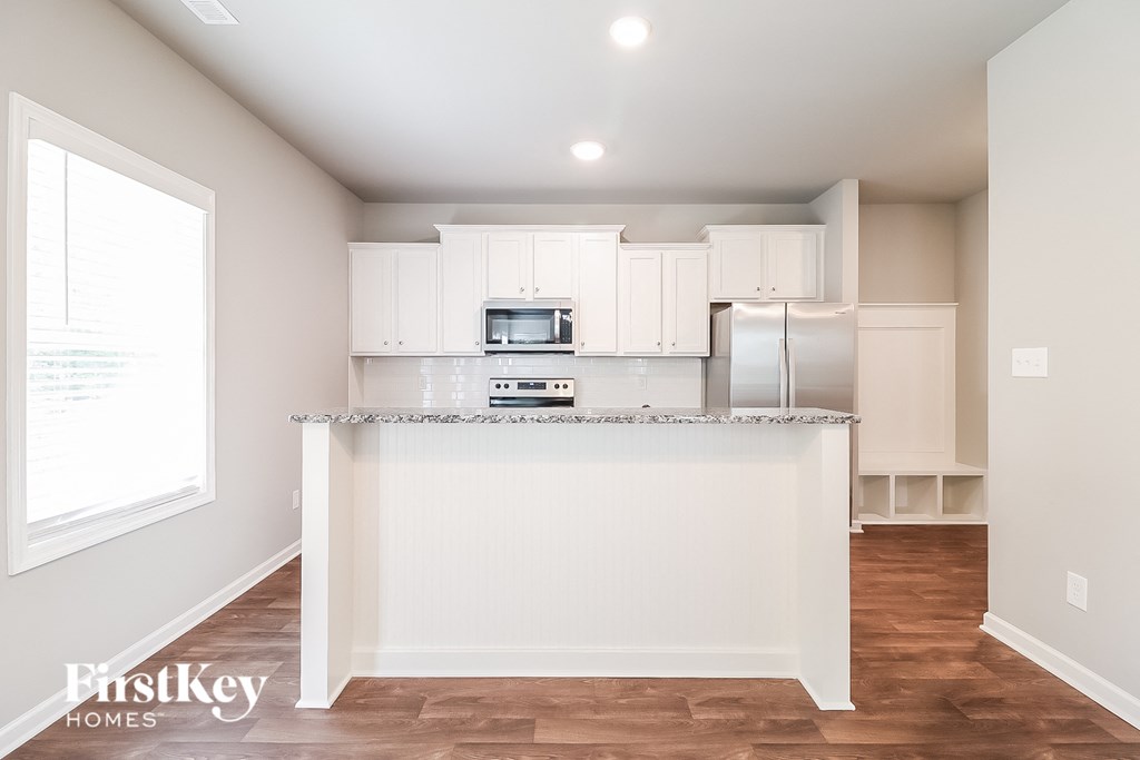 a kitchen with white cabinets and a marble counter top