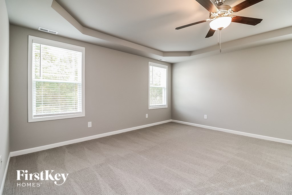 an empty living room with a ceiling fan and two windows