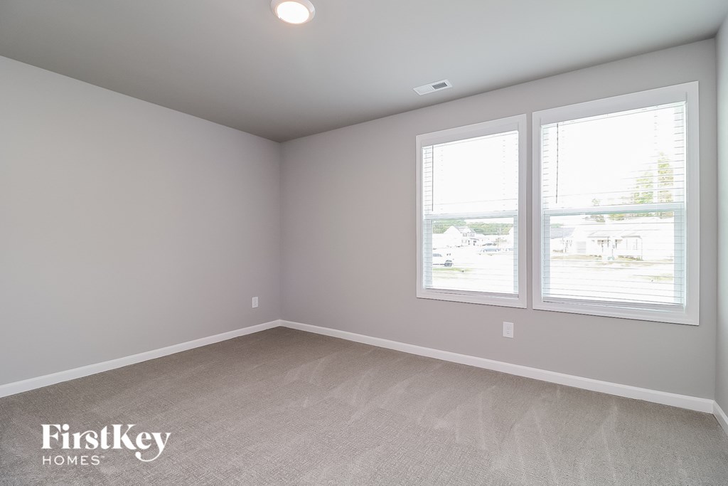 a bedroom with three windows and a carpeted floor