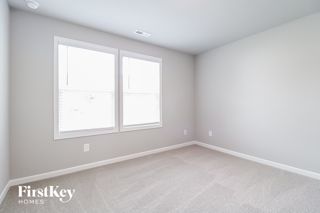 a bedroom with two windows and a carpeted floor