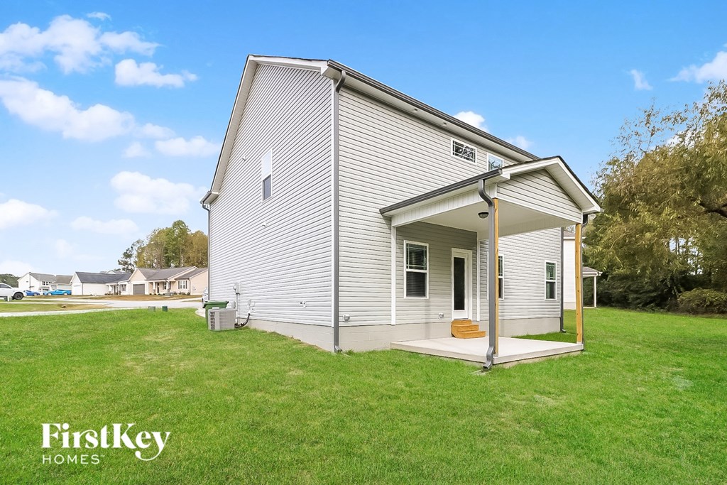 a small white house with a porch and a grassy yard