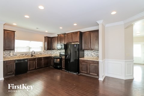 A kitchen with wooden cabinets and a black refrigerator.