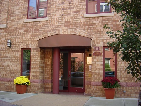 A building with a red door and windows with flower pots on the side.