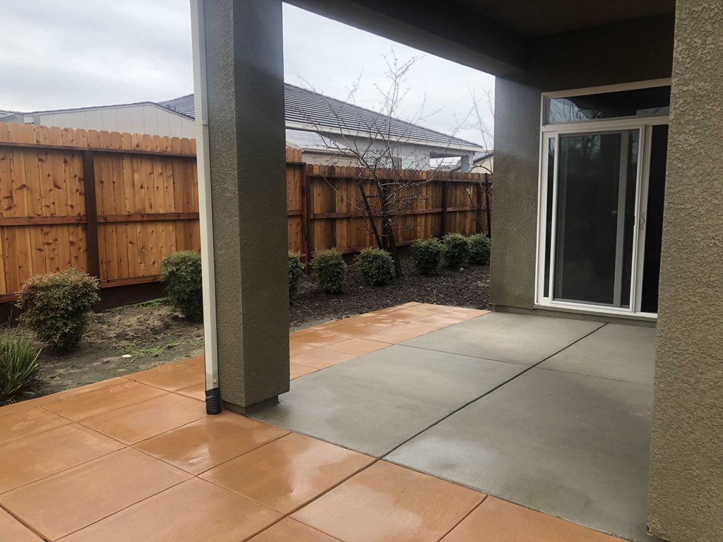 a patio with a tiled floor and a wooden fence