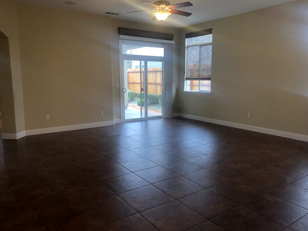 an empty living room with a ceiling fan and a sliding glass door