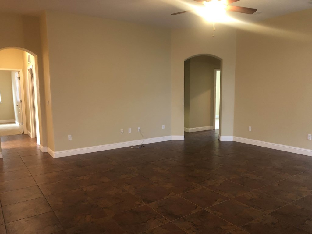 an empty living room with tile floors and a ceiling fan