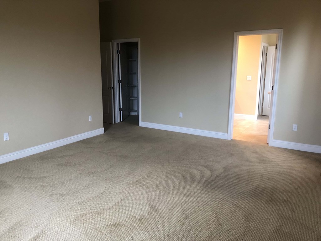 a empty living room with carpet and a door to a hallway