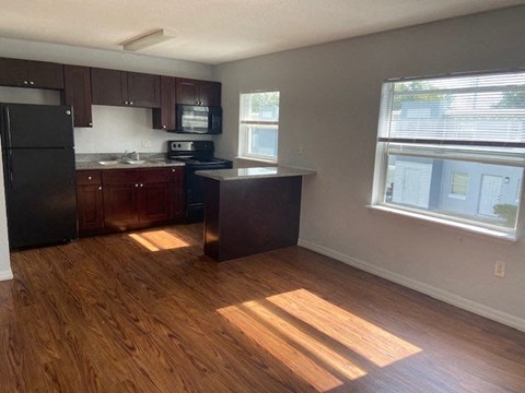 an empty kitchen with wooden floors and a window