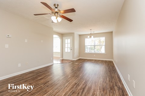 A spacious room with wooden floors and a ceiling fan.