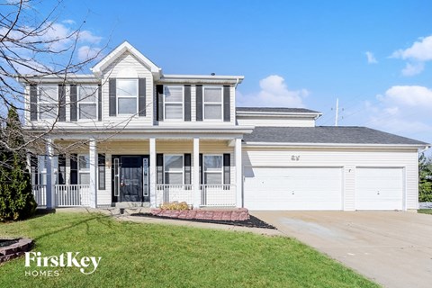 a white house with white garage doors and a lawn