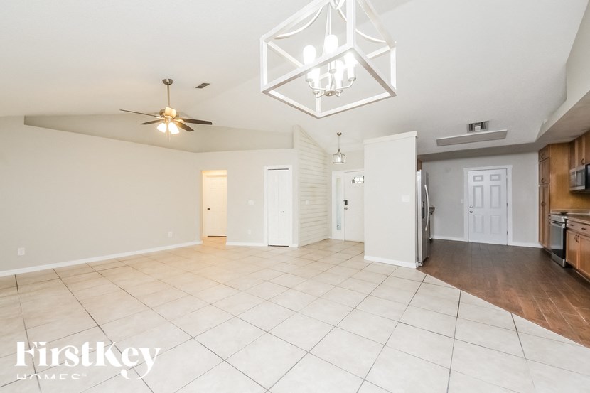 a kitchen and living room with a white tile floor and a chandelier