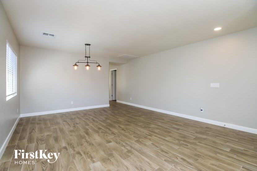 A spacious room with wooden flooring and a chandelier.