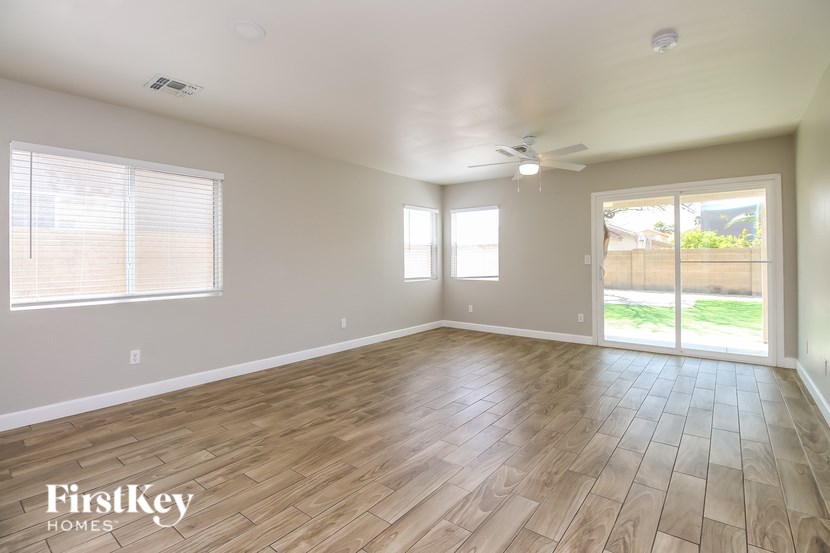 A spacious room with wooden flooring and a sliding glass door leading to a backyard.