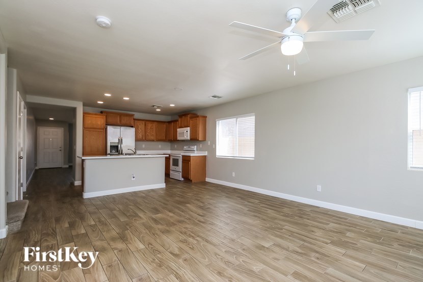 A spacious kitchen and living room with wooden floors and a ceiling fan.
