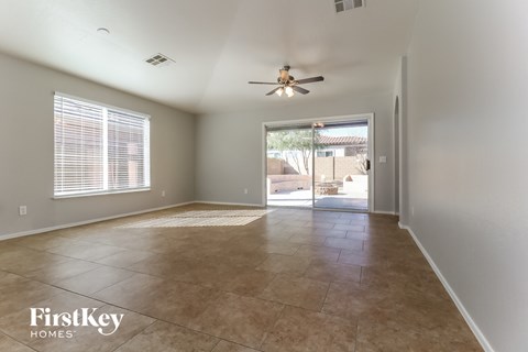 an empty living room with a ceiling fan and a door to a patio