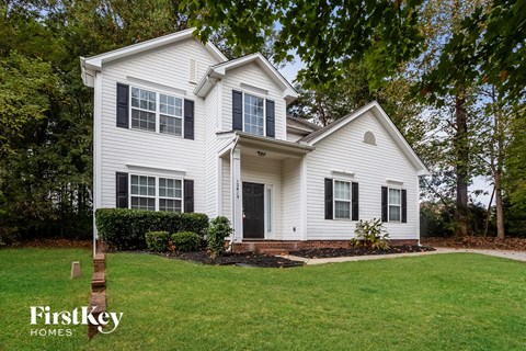 a white house with black shutters and a lawn