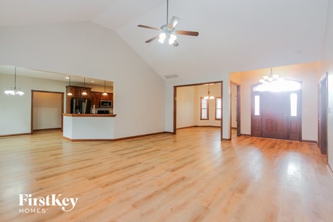 an empty living room with wood floors and a ceiling fan