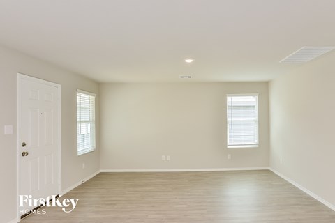 A spacious room with a white door and a window with blinds.