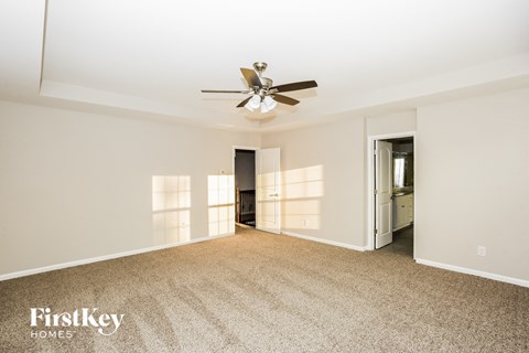 A spacious room with a ceiling fan and a carpeted floor.