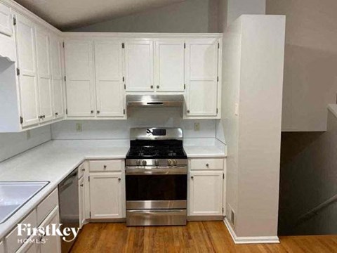 A kitchen with white cabinets and a stainless steel stove top.