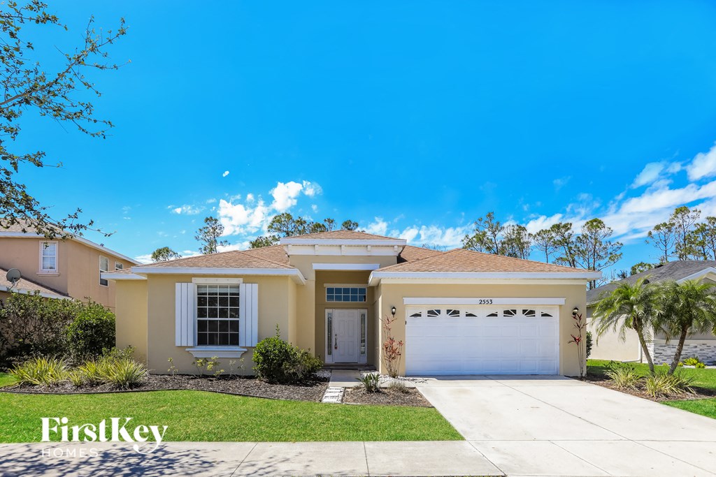 a beige house with a white garage door and a lawn