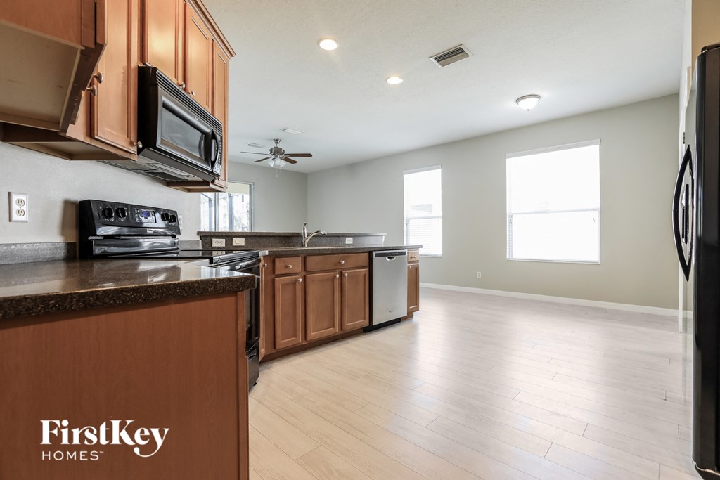 a kitchen with wood flooring and wooden cabinets and stainless steel appliances